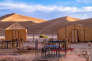 um grupo de mesas e tendas no deserto em Bivouac Dune Iriki em Foum Zguid