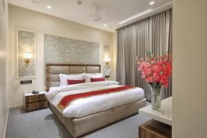 ein Schlafzimmer mit einem großen Bett und einer Vase aus Blumen in der Unterkunft Hotel Royal 9 in Meerut