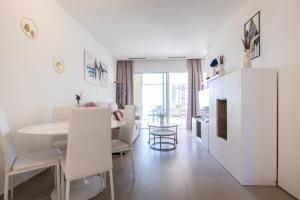 Il comprend un salon blanc avec une table et une cuisine. dans l'établissement INTEMPO SKY Apartments 034, à Benidorm