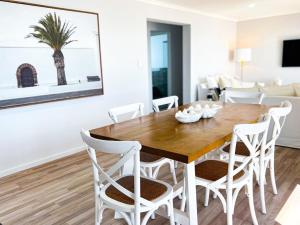 a dining room with a wooden table and white chairs at The Sandcastle House at Pelican Point in Carpenter Rocks