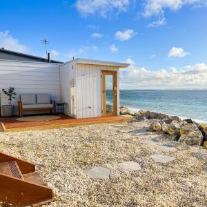 a small white building on a beach with the ocean at The Sandcastle House at Pelican Point in Carpenter Rocks