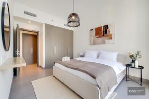 a white bedroom with a large bed and a mirror at High Floor - Stunning Location - Canal View in Dubai