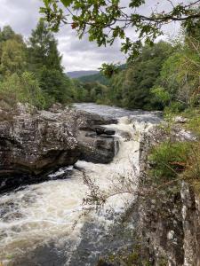 a river with rapids on the side of a mountain at Torgoyle Cottage in Inverness