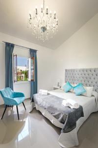 een witte slaapkamer met een groot bed en een kroonluchter bij Villacana 2907 in Estepona