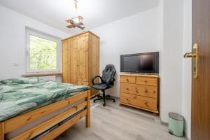 um quarto com uma cama, uma televisão e uma cadeira em Private House em Hanôver