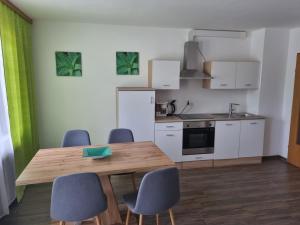 a kitchen with a wooden table and blue chairs at Appartementhotel Rutar Lido in Eberndorf