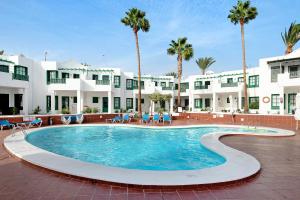 einen großen Pool in einem Innenhof mit Palmen in der Unterkunft Spacious Sunny Relaxing Lanzarote in Puerto del Carmen