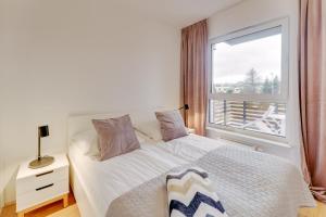 a bedroom with a white bed and a window at Apartament SAND SurfingBird Dźwirzyno in Dźwirzyno