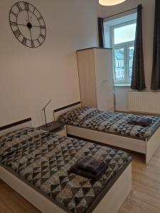 two beds in a room with a clock on the wall at Suwałki Centrum Apartments 1 & 2 in Suwałki