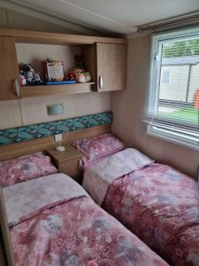 Duas camas num pequeno quarto com uma janela em Beautiful 3 bed holiday home em Port Seton