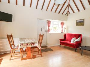 a dining room with a table and a red chair at Byre Cottage 1 in Pulborough
