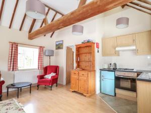 a kitchen with a red chair and a table at Byre Cottage 1 in Pulborough