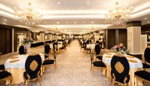 a banquet hall with tables and chairs and chandeliers at Hotel CASA Aishbagh in Lucknow