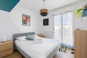 a bedroom with a white bed and a large window at Le Manuka - avec terrasse et parking in Nantes