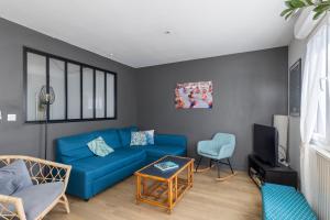 a living room with a blue couch and a tv at Le Manuka - avec terrasse et parking in Nantes