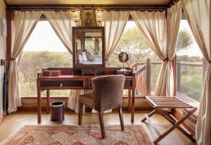 een kantoor met een bureau, een spiegel en een raam bij TARANGIRE KURO TREETOP LODGE in Manyara