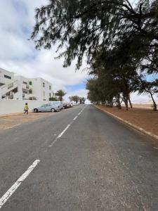 an empty road with a car parked on the side at Garajonay in Puerto del Rosario