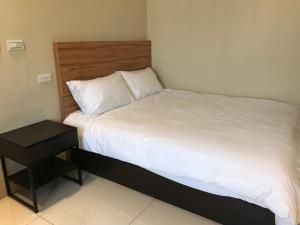 a bed with white sheets and a wooden headboard at Kinmen Old Town Homestay in Jincheng