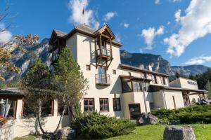 a large white building with mountains in the background at Hotel Restaurant Südrast Dreiländereck in Arnoldstein