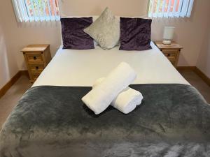 a bedroom with a bed with two towels on it at Holly Cabin with Hot Tub in York
