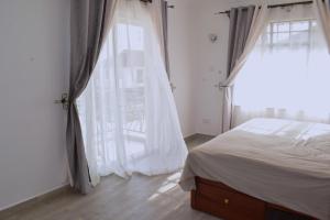 sypialnia z łóżkiem i dużym oknem w obiekcie Cheerful 4-bedroom with pool w mieście Athi River
