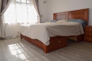 a bedroom with a bed with a wooden headboard and a window at Cheerful 4-bedroom with pool in Athi River