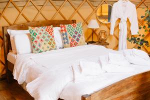 een bed met witte lakens en kussens in een kamer bij Yurtshire Fountains - Wensley Yurt in Ripon