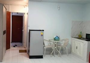 a small kitchen with a table and a refrigerator at ห้องใหญ่-ห้องพักรายวัน เมืองทองธานี เรือนศรีตรัง in Nonthaburi