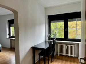 ein Esszimmer mit einem Tisch und Stühlen sowie 2 Fenstern in der Unterkunft Monteurwohnung Mönchengladbach Geroweiher in Mönchengladbach