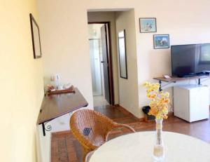 uma sala de estar com uma mesa e uma televisão em Pousada Caminho da Serra em São Roque de Minas