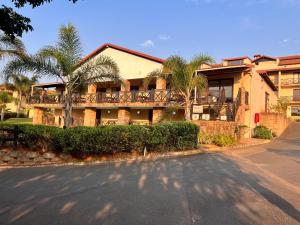 a house with palm trees in front of a street at Ocean View Villas: Port Edward Unit H09 in Port Edward