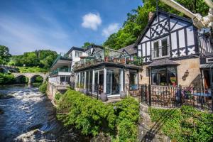 a house next to a river with a bridge at The Chainbridge Hotel in Llangollen