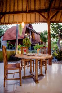 een houten tafel en stoelen op een patio bij The Granyam Garden Cottage in Nusa Penida