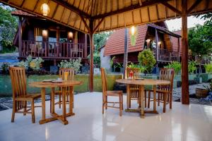 a patio with two tables and chairs under a pavilion at The Granyam Garden Cottage in Nusa Penida