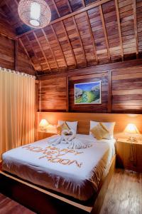 1 dormitorio con 1 cama grande y paredes de madera en The Granyam Garden Cottage, en Nusa Penida