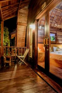 a room with a bed and a chair on a porch at The Granyam Garden Cottage in Nusa Penida