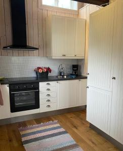 a kitchen with white cabinets and a black stove at Bo i egen stuga på härlig ölandsgård in Köpingsvik