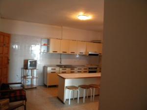 a kitchen with white cabinets and a kitchen island with stools at Apartamentos Restinga in La Restinga