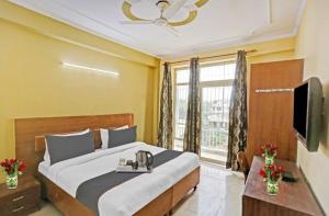 een slaapkamer met een groot bed en een televisie bij Hotel Ashvins Palace in Gurgaon