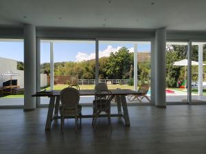 stół jadalny z krzesłami i duże okno w obiekcie Villa de lujo en Jarandilla w mieście Jarandilla de la Vera
