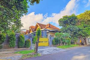 a house with a yellow gate on a street at OYO 91738 Ciung Wanara Guest House in Denpasar
