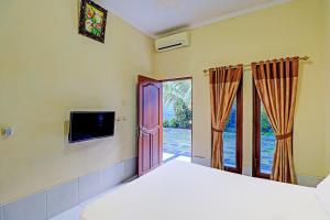 Schlafzimmer mit einem Bett und einer Tür mit einem TV in der Unterkunft OYO 91738 Ciung Wanara Guest House in Denpasar