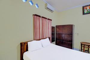 een slaapkamer met een bed, een tafel en een stoel bij OYO 91738 Ciung Wanara Guest House in Denpasar