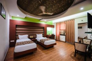 a hotel room with two beds and a tv at HOMANSH GALAXY HOTEL in Kānpur