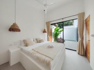 a white bedroom with a large bed and a window at Bahala Na Villas in El Nido