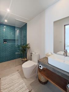 a bathroom with a toilet and a sink and a tub at Bahala Na Villas in El Nido