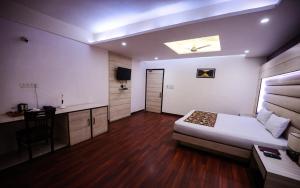 a bedroom with a bed and a desk and a table at HOMANSH GALAXY HOTEL in Kānpur
