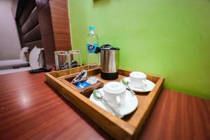 a tray with cups and a coffee maker and a bottle of water at HOMANSH GALAXY HOTEL in Kānpur