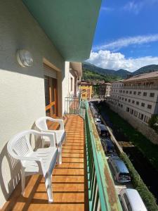 a balcony with white chairs and a view of a city at Apartaments Sant Antoni in Ribes de Freser