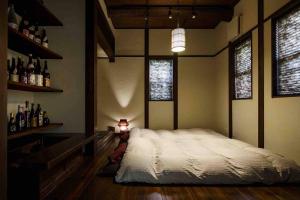1 dormitorio con 1 cama en una habitación con botellas de vino en AsoSweet en Aso